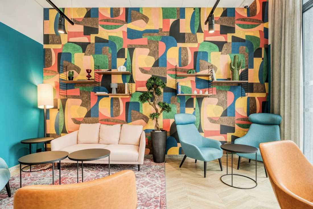 Espace lounge du B&B Hôtel Namur avec un papier peint aux motifs colorés
